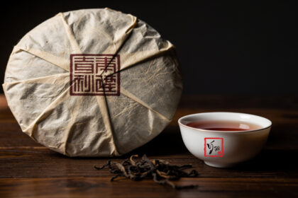 Bánh trà phổ nhĩ 357g gói giấy in mã số đặt trên bàn gỗ cùng chén trà