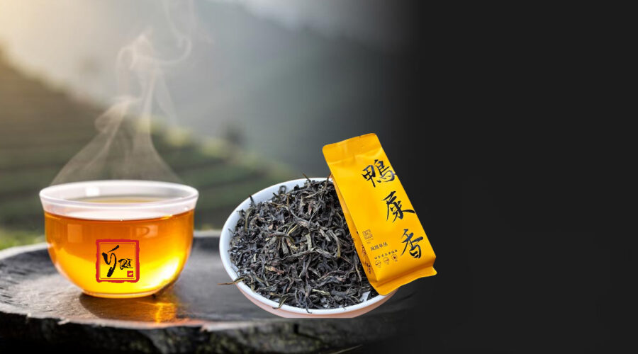 Chén trà phượng hoàng đơn tùng nước vàng óng bên lá trà xoăn dài, nền núi Phượng Hoàng mờ sương