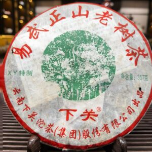 Bánh phổ nhĩ Dị Võ Lục Thái Dương 2010 của nhà máy Hạ Quan, sinh trà 357g trên giá gỗ